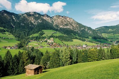 Blick auf Alpbach, im Vordergrund eine kleine Tenne, im Hintergrund die Bergkulisse mit grünen Bäumen  | © Alpbachtal Tourismus | Alberto Campanile 