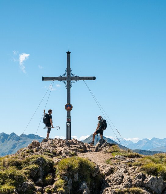 Ein Paar genießt gemeinsam den Gipfelsieg am Gipfelkreuz Gratlspitze im Alpbachtal  | © Alpbachtal Tourismus | shootandstyle 