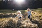 Zwei Kinder (ein Mädchen und ein Junge) springen im Heuhaufen hin und her  | © Alpbachtal Tourismus | Mathäus Gartner 