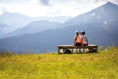 Zwei Kinder (ein Mädchen und ein Junge) sitzen gemeinsam auf der Rastbank und genießen  die Aussicht auf das Alpbachtal  | © Alpbachtal Tourismus | shootandstyle