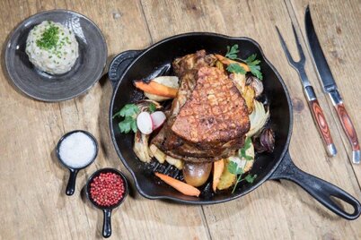Auf diesem Bild zu sehen ist eine Pfanne voller Gemüse, darauf ein Stück Schweinebraten, links daneben befindet sich noch ein kleiner Teller mit einem Speckknödel , mit Schnittlauch garniert  | © Alpbachtal Tourismus 