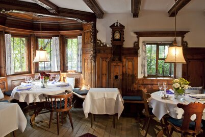 Auf dem Bild zu sehen ist eine rustikale Gaststube mit zwei voll eingedeckten Tischen | © Alpbachtal Tourismus 