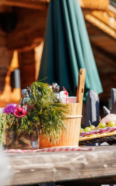 Ein Kellner bringt einer Frau eine Hüttenjause, auf der Bischofer Käsealm in Alpbach  | © Alpbachtal Tourismus | Maximalgrafik 