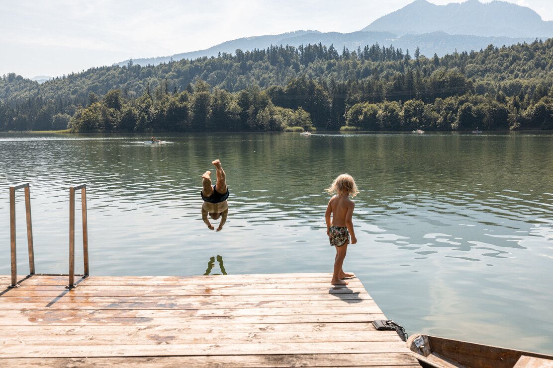 Auf diesem Bild zu sehen ist ein kleiner Junge, welcher seinem Papa beim Sprung ins Wasser beobachtet  | © Alpbachtal Tourismus | shootandstyle 