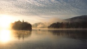 Auf diesem Bild zu sehen ist der Reintalersee in Kramsach, umgeben von einer Nebelschicht, in der Mitte zu sehen ein kleines Fischerboot  | © Alpbachtal Tourismus | Christian Vorhofer 