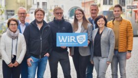 Der gesamte Vorstand der WiR Alpbachtal, 3 Frauen und 5 Männer, stehen im Stadtzentrum von Rattenberg und in der Mitte wird eine blaue Tafel mit der Aufschrift "WiR Alpbachtal" gehalten. | © WiR Alpbachtal