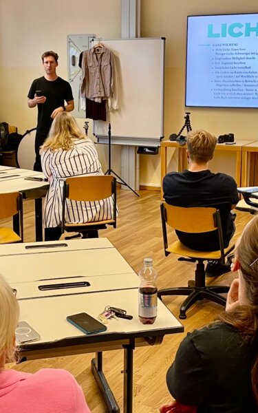 Netzwerktreffen mit Maximalgrafik | © WiR Alpbachtal Personen sitzen in einer Schulklasse und hören einem Vortragenden zu, welcher zu einer Präsentation spricht, auf der elektronischen Tafel ist eine Folie mit der großen Überschrift "Licht" zu lesen. | © WiR Alpbachtal