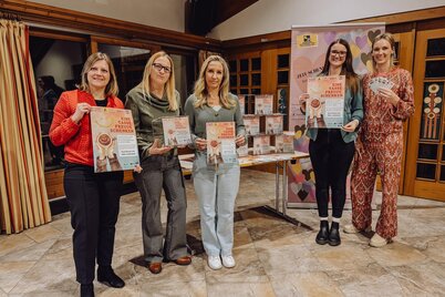 5 Frauen stehen vor einem Tisch mit Plexiglasboxen und einem Roll-up des Freiwilligen Zentrum Kitzbüheler Alpen, zwei Frauen halten ein Plakat des Projekts "Eine Tasse Freude schenken" in der Hand, eine Frau eine Plexiglasbox für die Gutscheinsammlung. | © WiR Alpbachtal